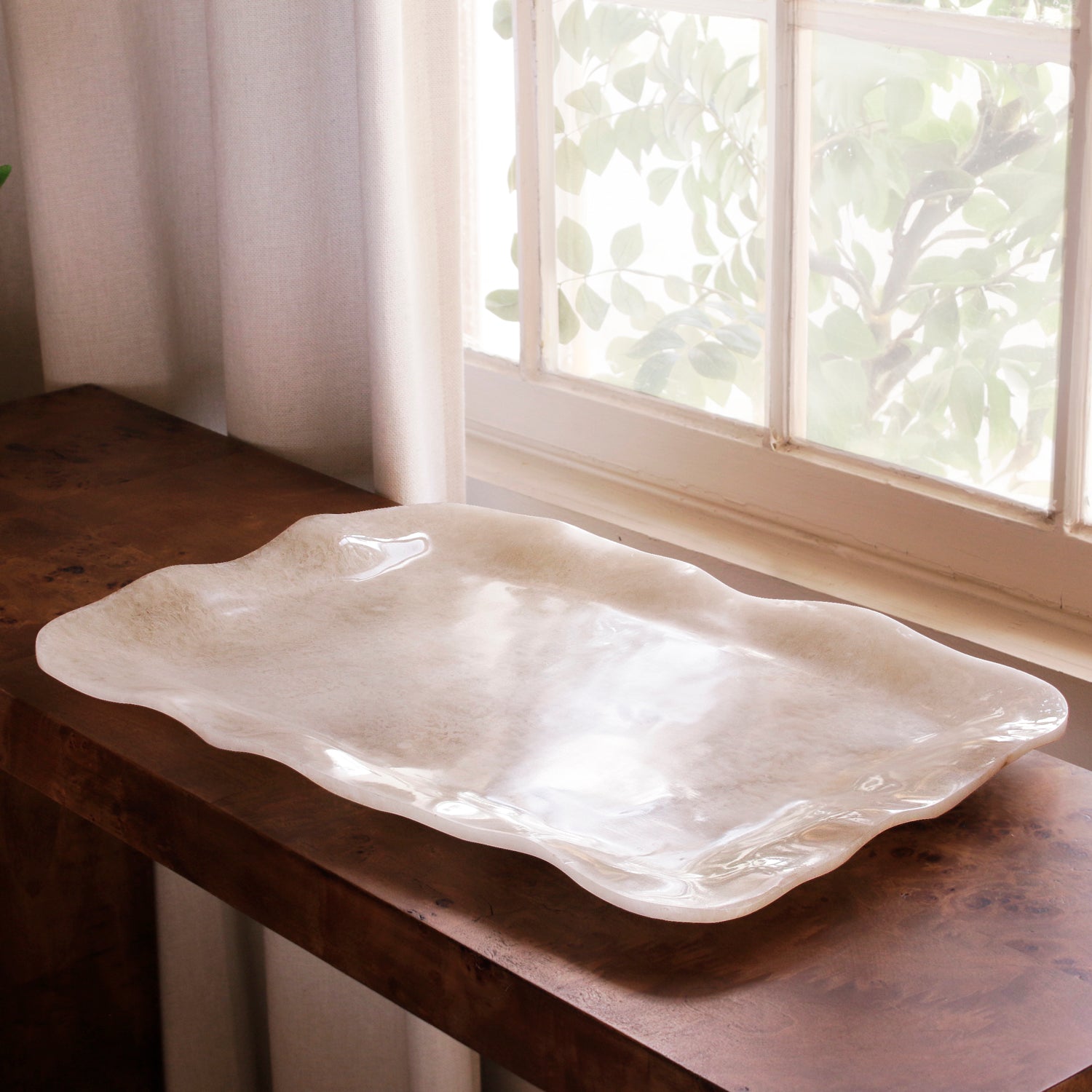 White alabaster resin tray on a wooden surface with a window in the background
