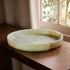 Green marble pattern resin tray on a wooden surface with a window in the background