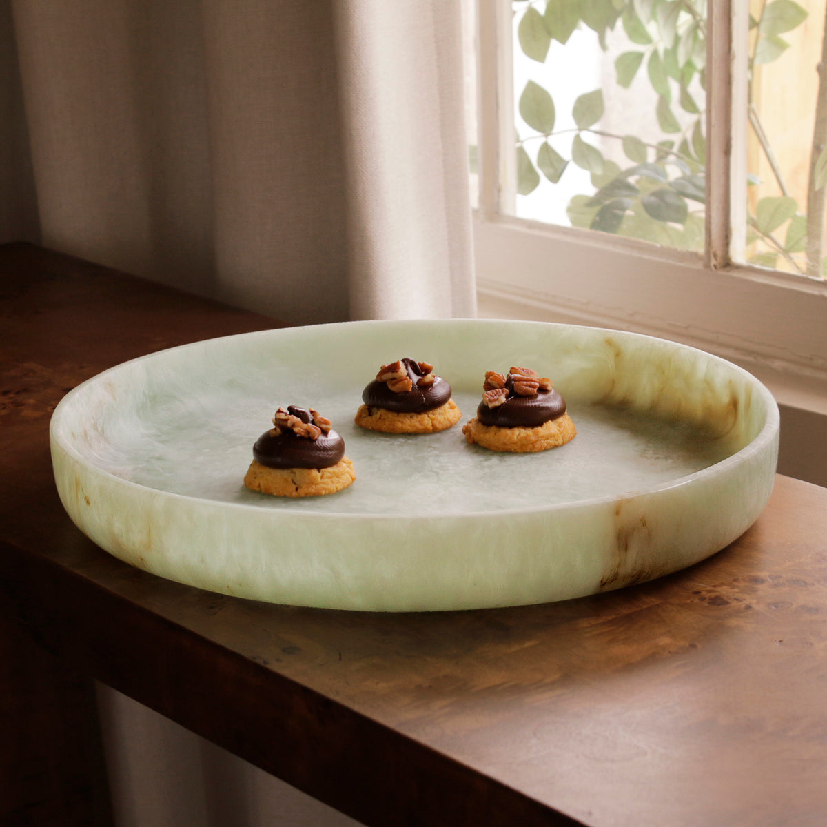 Green marble pattern resin tray with cookies on a wooden surface near a window