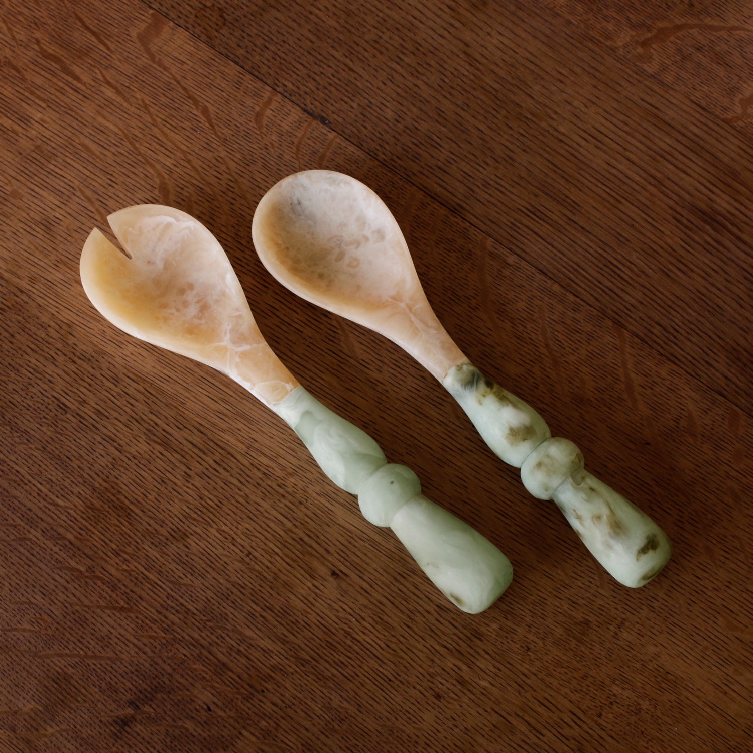 Two Salad Servers with jade swirl marble pattern resin handles on a wooden surface