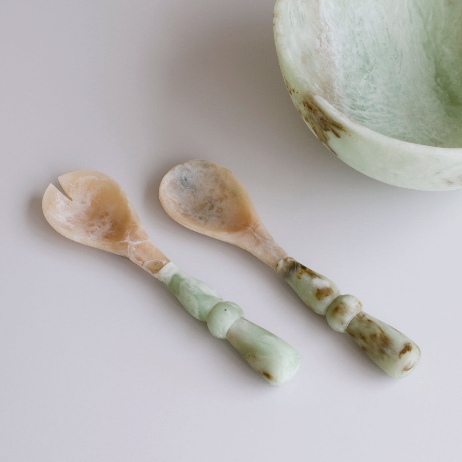 Two Two Salad Servers with jade swirl marble pattern resin handles on a light background