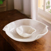 White resin bowl on a wooden surface with a soft, natural light background