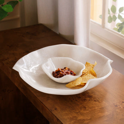 White resin bowl with a smaller bowl inside on a wooden surface, containing chips and dip.