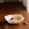 White resin bowl with nuts on a wooden surface