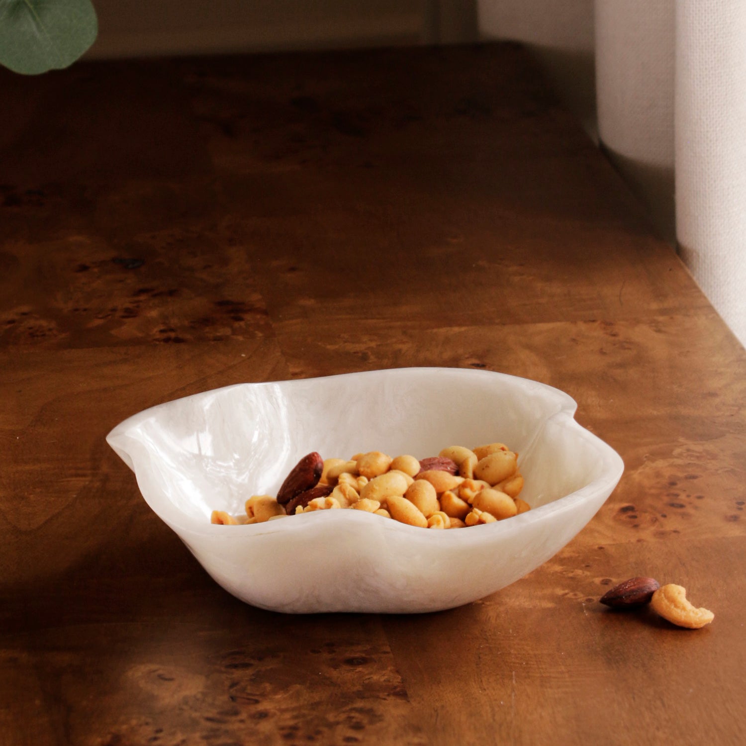 White resin bowl with nuts on a wooden surface