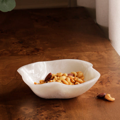 White resin bowl with nuts on a wooden surface