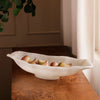 White resin bowl with fruits on a wooden surface near a window