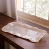 White alabaster resin tray on a wooden surface with a window in the background