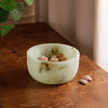 Jade swirl marble pattern resin bowl with nuts on a wooden surface