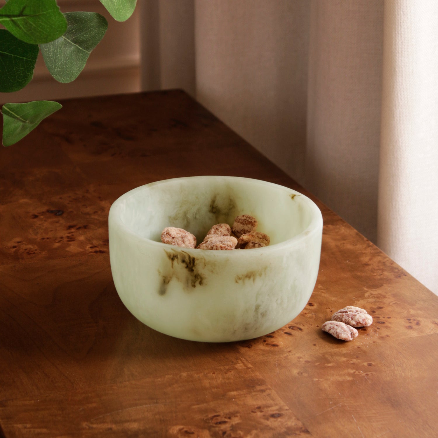 Jade swirl marble pattern resin bowl with nuts on a wooden surface