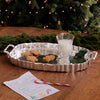 Silver tray with cookies, milk, and a candy cane in front of a Christmas tree.
